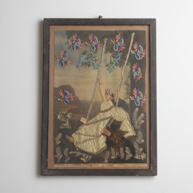 Decorative wall art with a woman on a swing and colorful birds in a wooden frame.