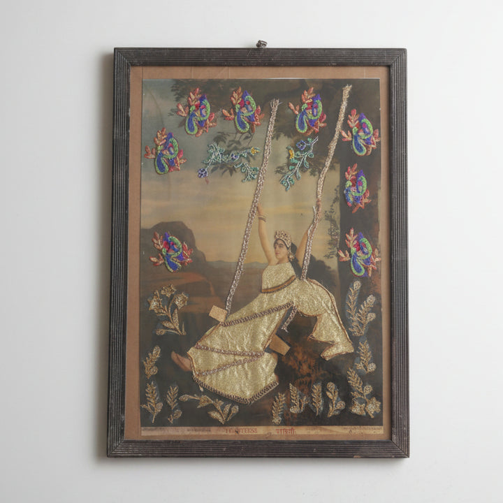 Decorative wall art with a woman on a swing and colorful birds in a wooden frame.